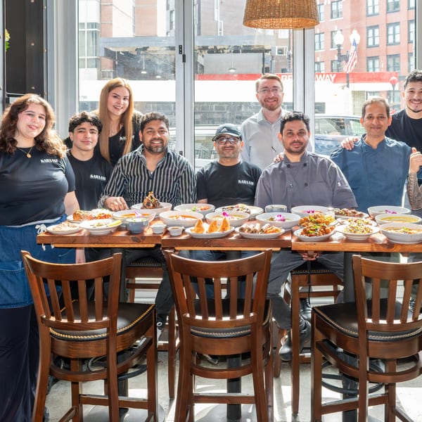 Kahaani restaurant staff and chefs pose with a table full of diverse Indian dishes.
